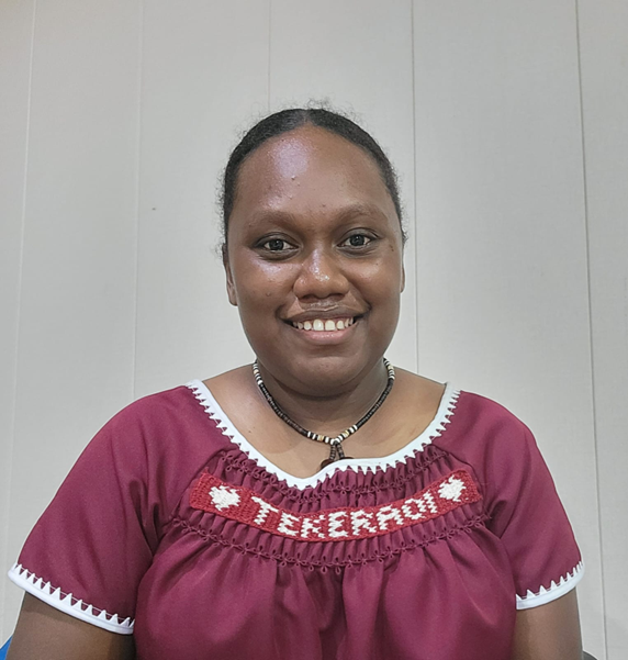 A headshot picture of Johnina. Johnina has her hair pulled back and is wear a read top with writing 'Tereraoi' on the top.