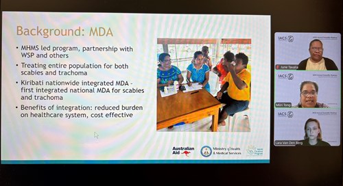 A picture of a laptop screen showing a presentation on the background of the MDA. There are 3 women in presenter mode on the righthand side of the screen.